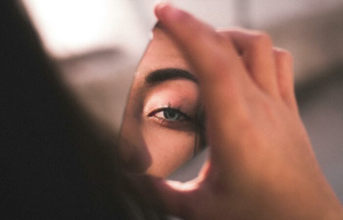 A captivating image of a woman's eye reflected in a broken mirror piece with soft lighting.