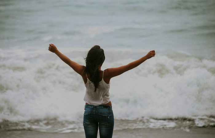 woman in white spaghetti strap top standing on the seashore