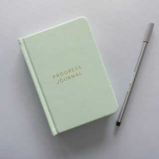 green leather tablet case beside black pen