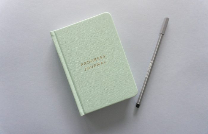 green leather tablet case beside black pen